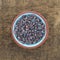 Himalayan black salt in a bowl on a wood board.