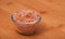 Himalayan pink salt in tiny transparent glass bowl on wood