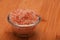 Himalayan pink salt in tiny transparent glass bowl on wood