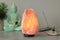 Himalayan salt lamp, buddha figure, incense and crystals on stone table near grey wall