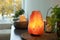 Himalayan salt lamp, houseplant and candles on table indoors, space for text