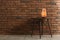 Himalayan salt lamp on table against  brick wall