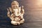 Hindu god Ganesh on black background. Statue on wooden table