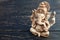 Hindu god Ganesh on black background. Statue on wooden table