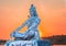 Hindu god lord shiva statue in meditation posture with dramatic sky at evening from unique angle