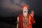 Hindu monk whose face smeared with ash stands in the ghats of the river Ganges