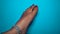 A Hindu woman wearing Silver paajeb Anklets in India. Female foot with red Nail polish isolated on blue background