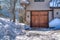 Hinged wooden garage door and snowy driveway viewed at the exterior of home