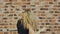 Hip hop blonde girl dancing in modern style over urban brick wall. Slow motion.
