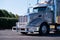 Hip powerful gray glossy big rig semi truck with grille guard an