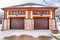 Hip roof garage exterior with two brown doors and wet snowy driveway in winter.