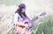 Hippie girl with the guitar walking on a meadow