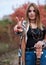 Hippie musician with acoustic guitar, showing piece sign with two fingers. Three-quarter portrait of young woman, wearing colorful