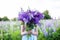 A hippy girl holding bouquet of wildflowers in her hands. Girl hid her face behind bouquet of lupins. Little Girl holds large bouq