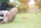 Hipster Asian man lying on the green grass and relaxing to listen music by white earplug from laptop while his hand holding his he