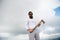 Hipster with beard on strict face holds axe, cloudy sky background. Man with beard holds axe while stand on top of