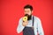 Hipster bearded baker hold glazed donut on red background. Cafe and bakery concept. Sweet donut from baker. Man bearded