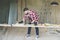 Hipster bearded man is carpenter, builder, designer stands in workshop, using laptop. On desk is construction tools