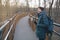 Hipster bearded millennial man in classic blue jacket with backpack drinking water from reusable stainless bottle while walking on