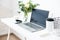 Hipster bloggers work place, laptop and flowers on white tabletop