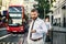 Hipster businessman waiting for the bus in London, checking the time.