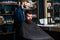 Hipster client getting haircut. Client with beard ready for trimming or grooming. Man with beard covered with black cape