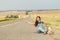 Hipster girl with backpack sitting on side of road. concept - hitchhiking, adventure, freedom. Copy space