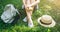 Hipster girl is holding melting ice-cream in hands. Woman sitting on green grass with straw hat. Cold summer desserts. Hot weather