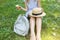 Hipster girl is holding melting ice-cream in hands. Woman sitting on green grass with straw hat. Cold summer desserts. Hot weather