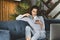 Hipster girl sitting in sofa and texting on smartphone. Entertaining and educating content online. Female communicating in social