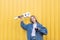 Hipster girl with ukulele and a film camera on the background of a yellow wall. Stylish girl holds ukulele in her arms