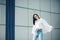 Hipster girl wearing blank white t-shirt, jeans and sunglasses posing against rough street wall, minimalist urban clothing style.