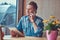 Hipster guy with a stylish haircut and beard sits at a table in a roadside cafe, talking on the phone and holds a tablet