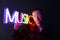 Hipster handsome man by neon signs. Multicolored neon sign music