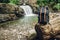 Hipster hiker tourist backpack on the background of the river and the waterfall , traveler relax holiday concept, travel