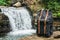 Hipster hiker tourist backpack on the background of the river and the waterfall , traveler relax holiday concept, travel