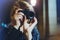 Hipster hiker tourist making photo, holding in hands camera on background of evening atmospheric city, photographer girl enjoy