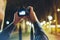 Hipster hiker tourist taking photo on camera on background of evening atmospheric city, photographer guy enjoying light of holiday