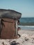 Hipster hiker tourister khaki backpack close up on background blue sea ocean horizon on sand beach, blurred panoramic seascape