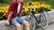 Hipster man with bicycle resting over flowerbed