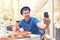 Hipster man sitting at table with large pizza and bruschetta holding glass of red wine taking selfie