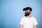 Hipster on smiling face enjoy virtual reality with gadget. Man with beard in VR glasses, light blue background. Digital
