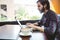 Hipster student using laptop in canteen