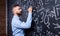 Hipster teacher writing on big blackboard with mathematical symbols