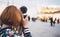 Hipster tourist girl hold in hands modern photo camera, take photography click on defocus background bokeh light in evening street