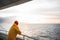 Hipster traveler wearing yellow raincoat and red hat enjoying beautiful ocean after storm