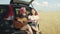 Hipster women playing guitar sitting in car trunk