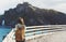 Hipster young girl with backpack enjoying sunset on seascape on peak mountain. Tourist traveler on background valley landscape vie