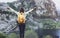 Hipster young girl with backpack standing on a rock with raised hands, enjoying lake on peak of foggy mountain. Tourist traveler