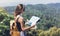 Hipster young girl with bright backpack enjoying panoramic mountain sea, using map and looking distance. Tourist traveler